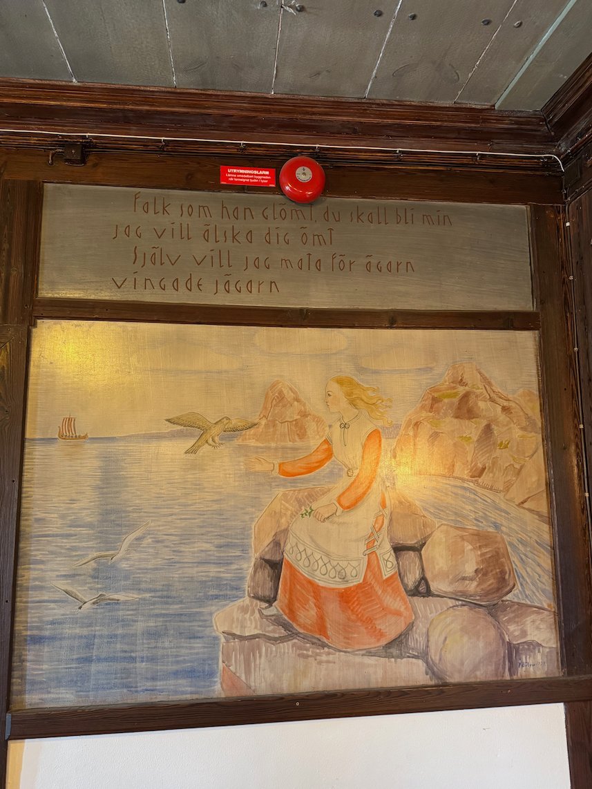 Painted wall panel at Odinsborg with a figure by the sea and old Swedish text above