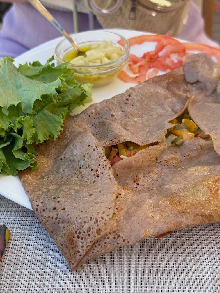A plate with a filled crepe, salad and tomato on Goree Island.
