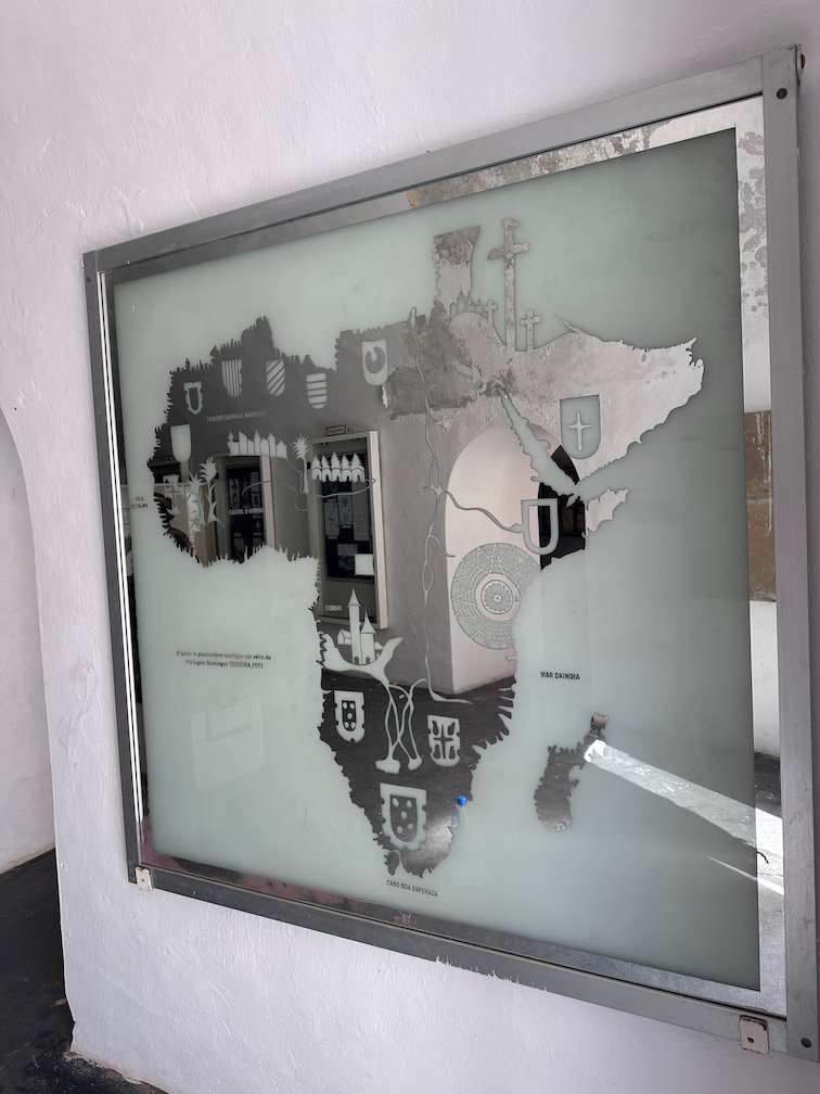 A glass panel with a map of Africa hangs on a wall in a Goree Island museum.