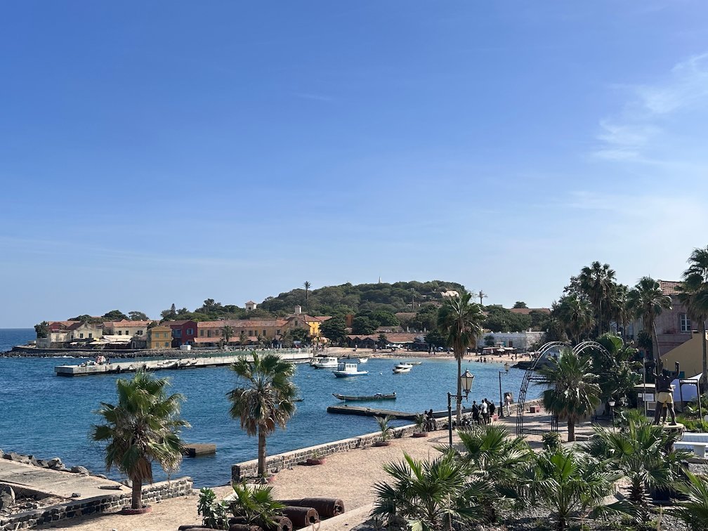 Palm trees line the small harbor and beach of Goree Island.
