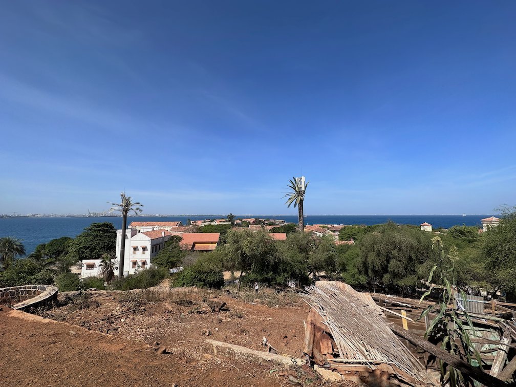 A view from the hill on Goree Island shows houses, palms and the sea.