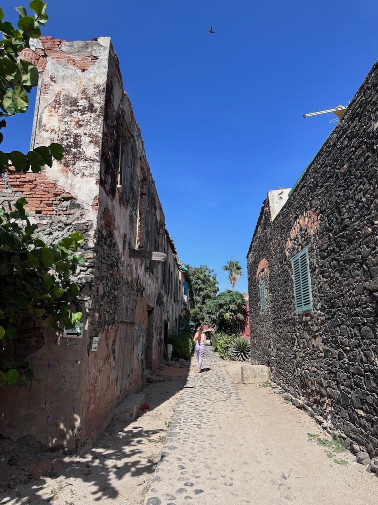 A narrow alley with stone walls leads through the old town of Goree Island.