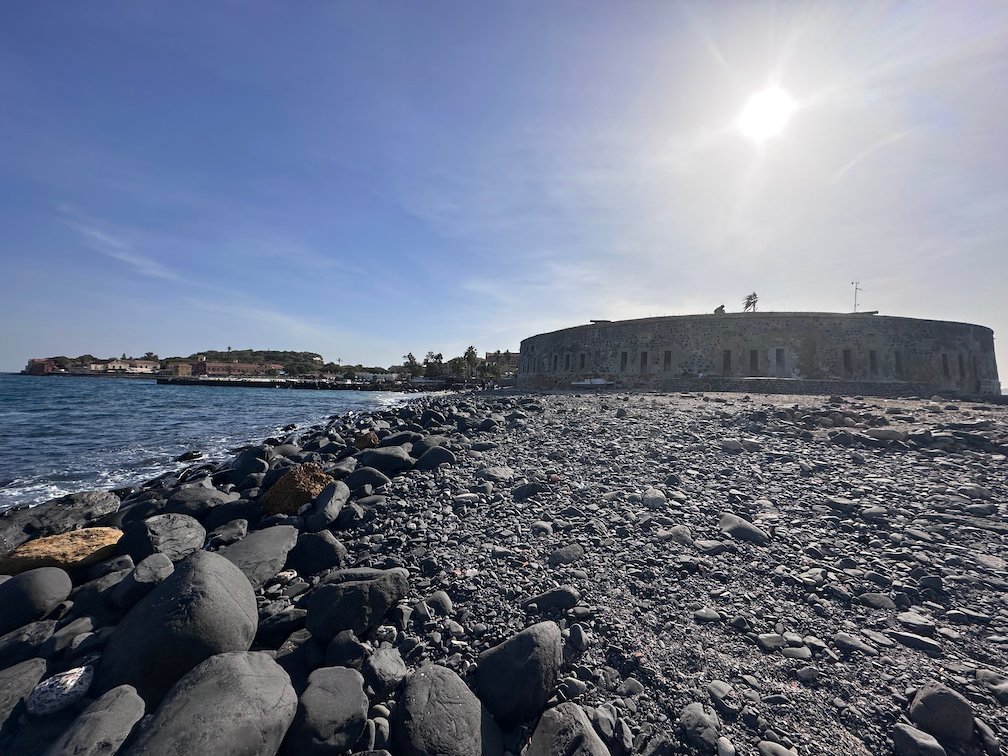A round stone fort stands on the rocky coast of Goree Island.