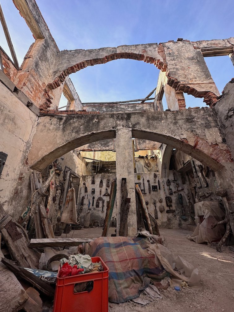A ruined house with an arch is full of old objects and art on Goree Island.