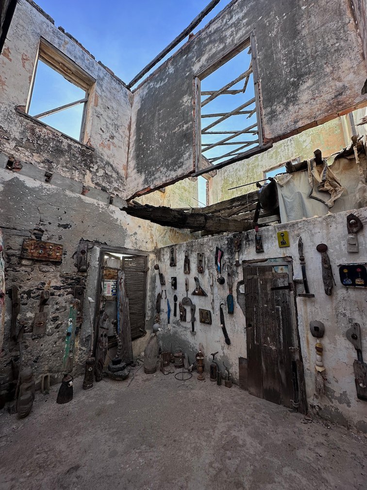 A roofless ruin with objects on the walls and an old door on Goree Island.