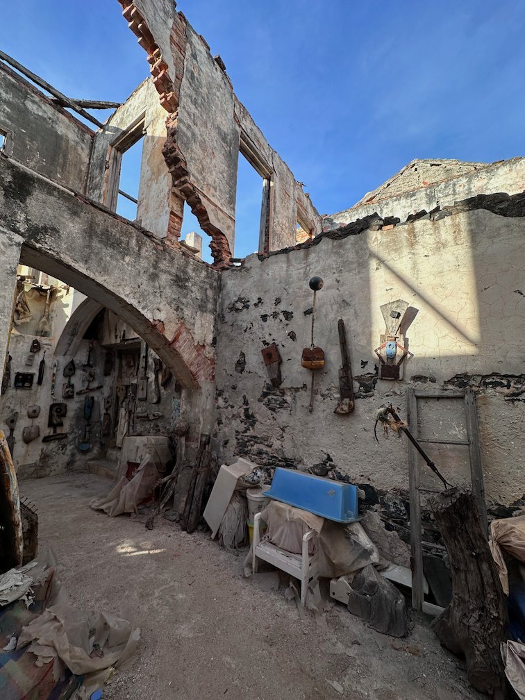 Old tools and objects hang on the walls of a roofless ruin on Goree Island.
