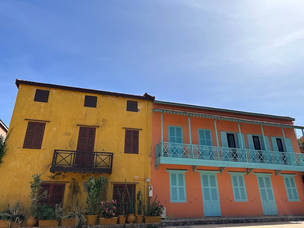 Yellow and orange colonial houses with balconies stand on Goree Island.