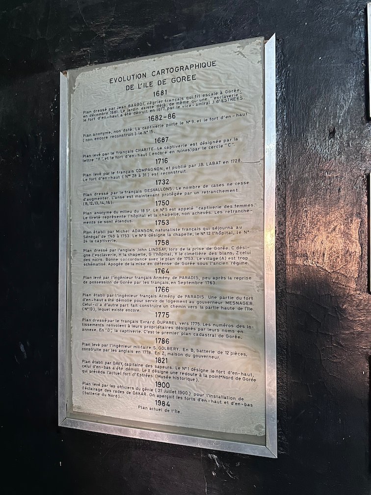 A metal plaque lists the history of maps of Goree Island.
