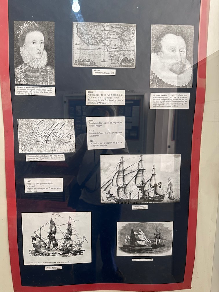 A museum board shows old ships, maps and portraits on Goree Island.