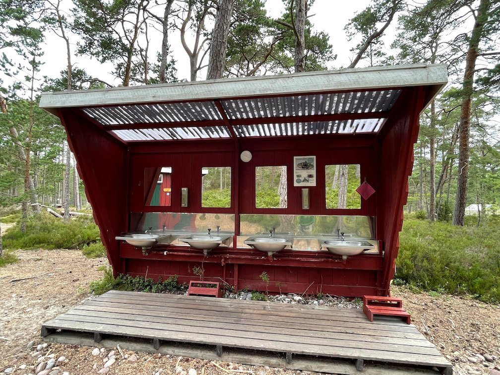 Diskbänkar utomhus under ett rött tak bland tallarna på Gotska Sandön