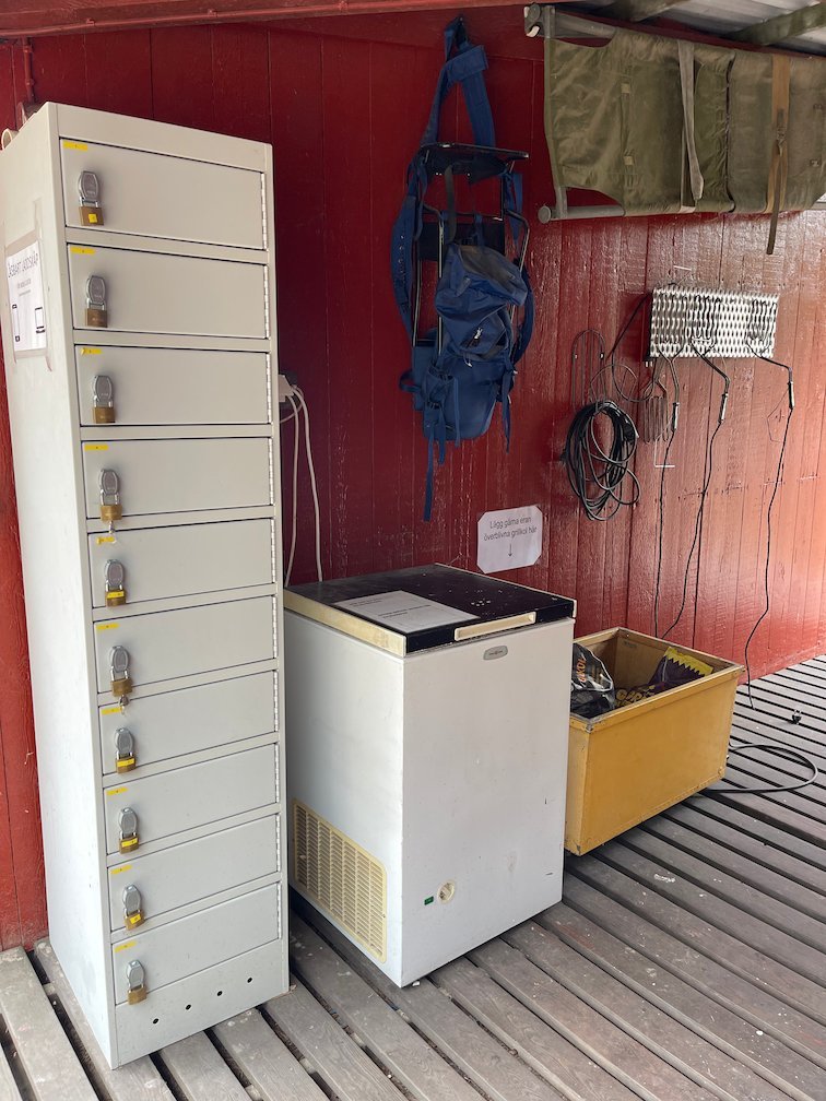 Förvaringsskåp och frysbox i ett rött skjul på lägerplatsen
