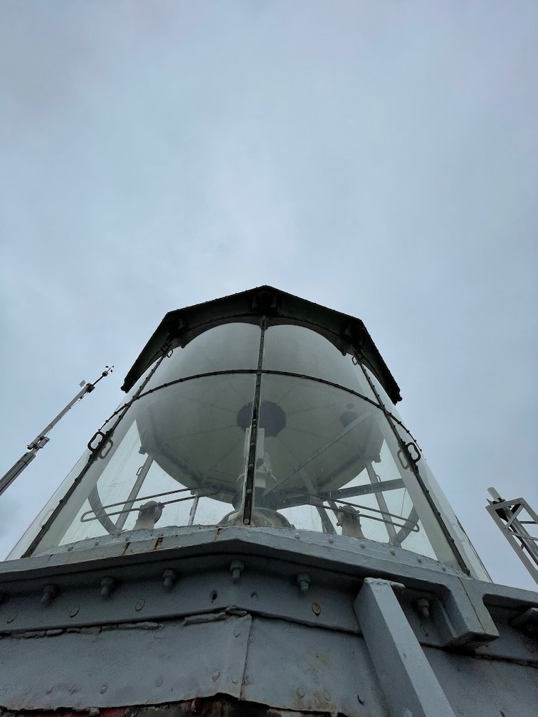 Fyrens lanternin med glas och metalltak mot grå himmel