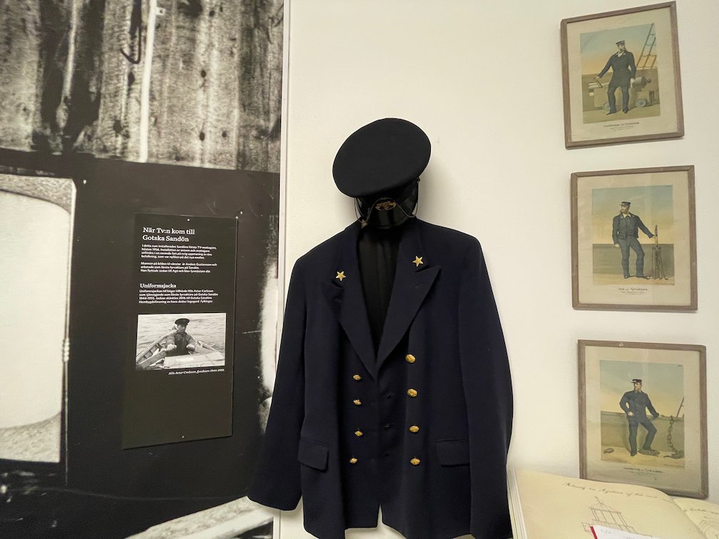 Fyrvaktarens mörkblå uniform med mössa och gamla porträtt