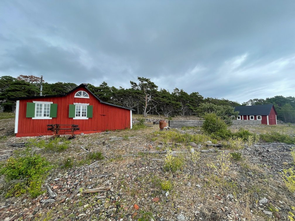 Röda stugor med gröna fönsterluckor på Hamnudden under grå himmel