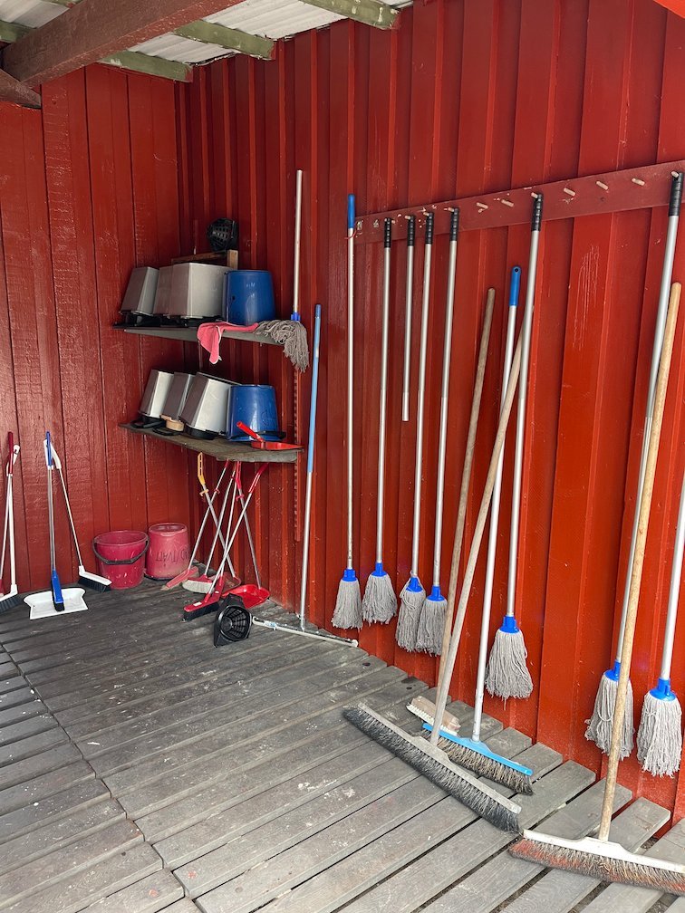 Rött förråd med moppar, kvastar och hinkar på lägerplatsen, Gotska Sandön