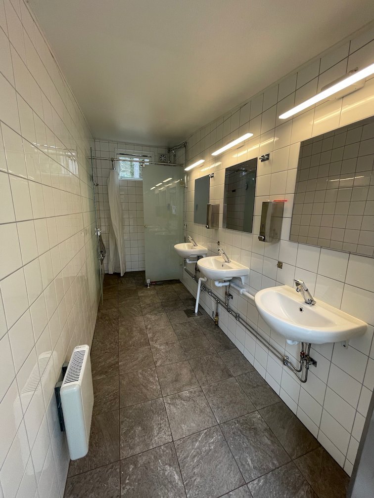 Vitkaklat tvättrum med handfat och speglar på lägerplatsen