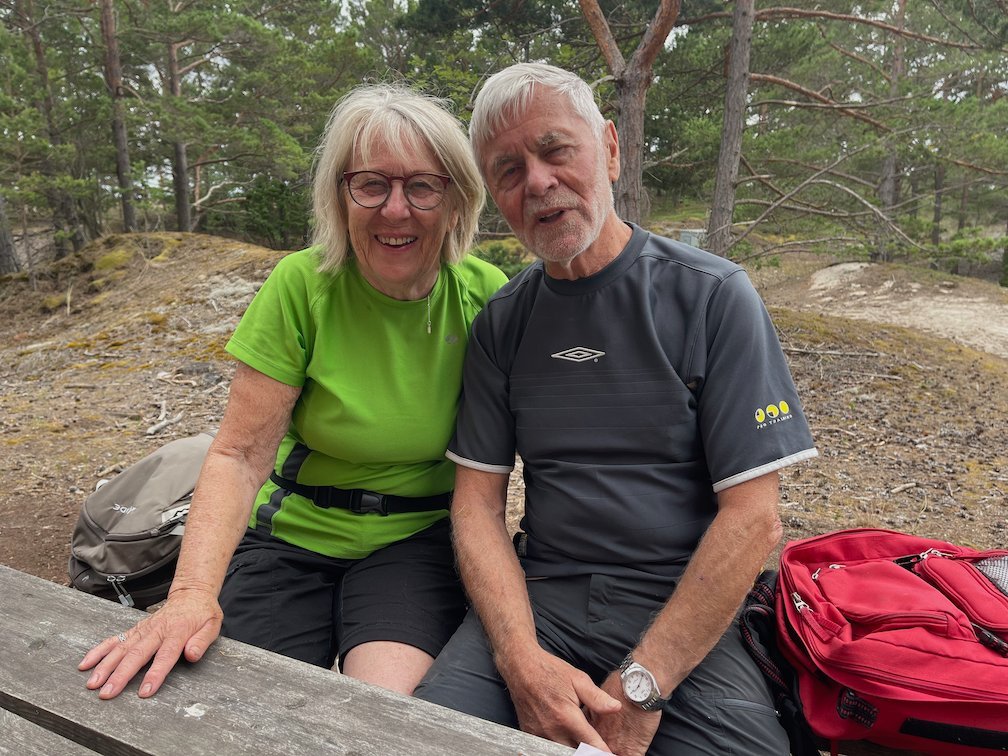 Två leende vandrare sitter vid ett bord i skogen på Gotska Sandön