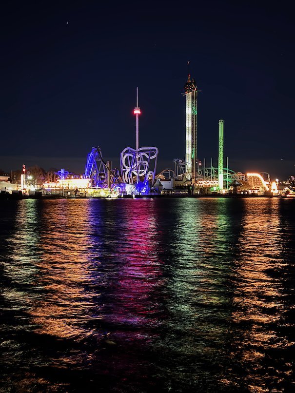 Gröna Lund amusement park at night, with colourful lights reflected in the dark water
