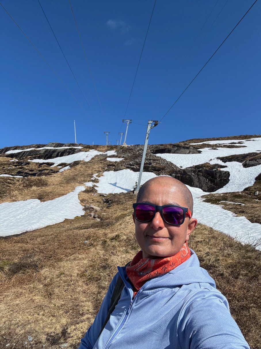 Selfie with sunglasses and a red scarf on the plateau with snow patches
