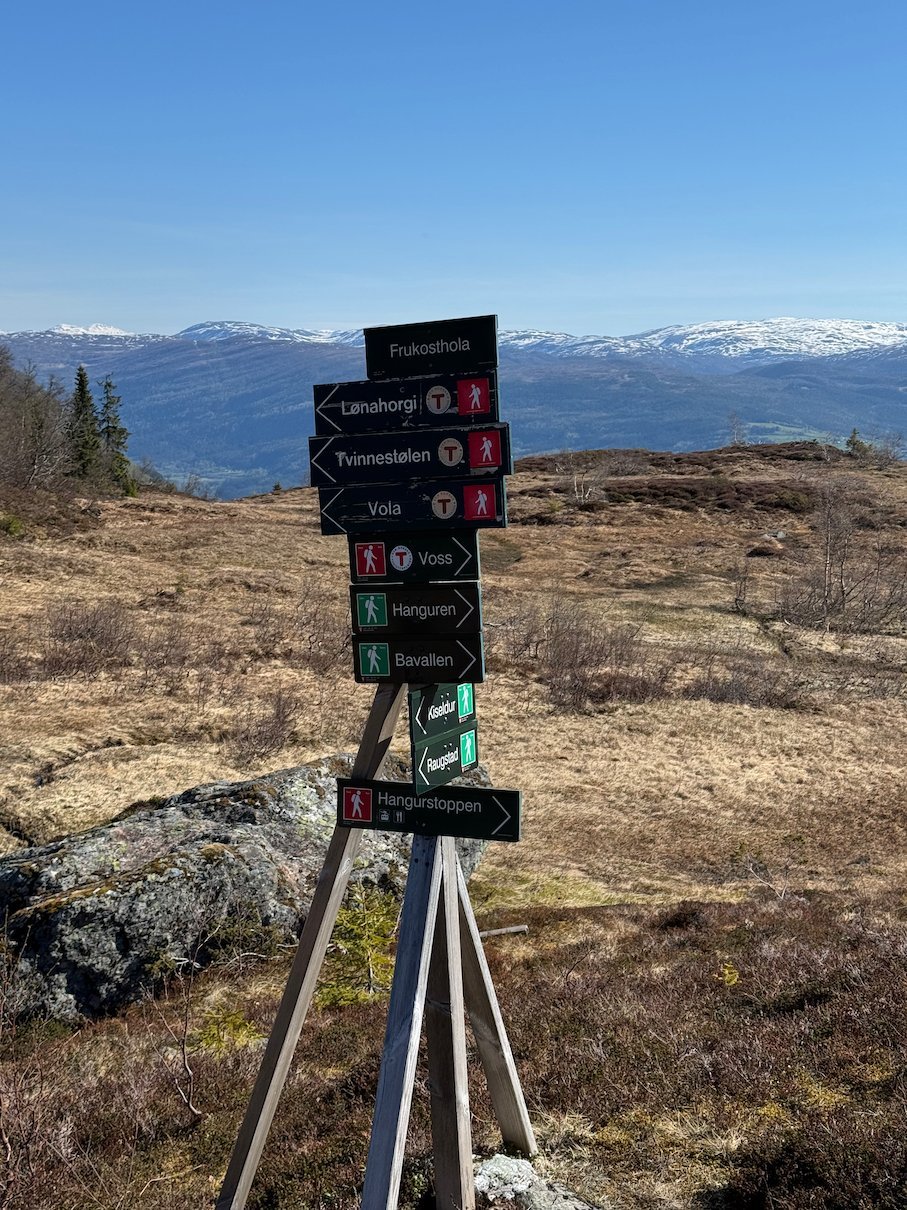 Trail signpost on the mountain plateau at Hanguren, with snowy peaks behind
