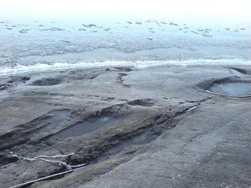 Thin ice and frozen water cover a flat rock at the shore on Kadermo island near Hanko.