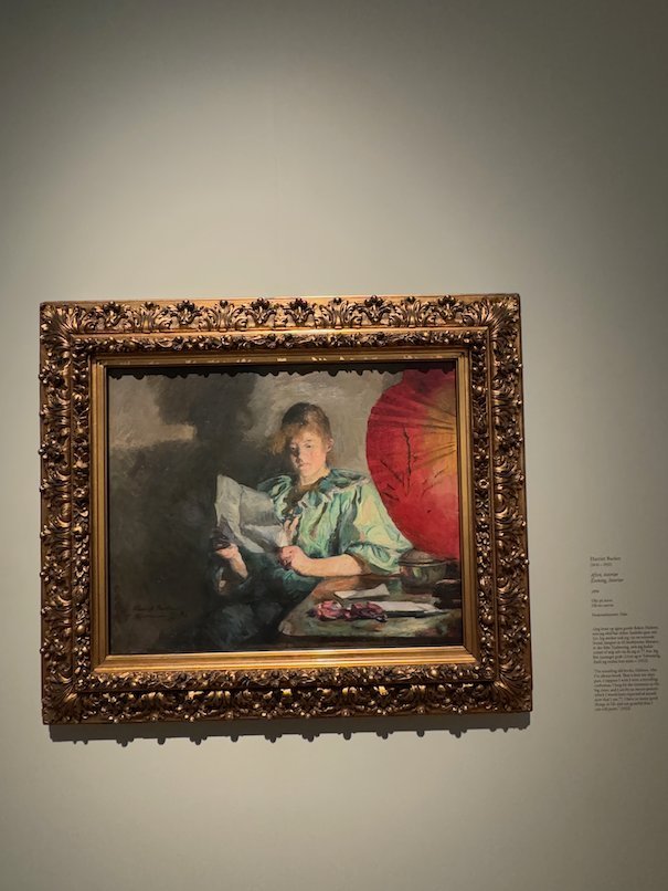 Painting by Harriet Backer of a woman who reads a letter in front of a red parasol