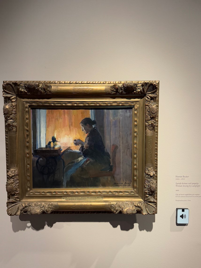 Painting by Harriet Backer of a woman by a lamp in a dark room