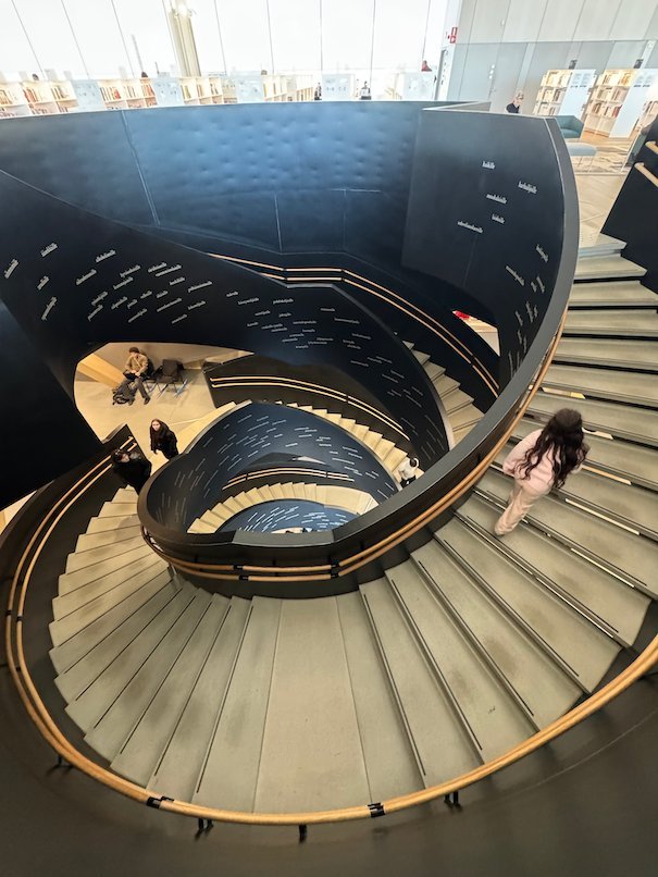 A dark spiral staircase curves between the floors of Oodi library in Helsinki.