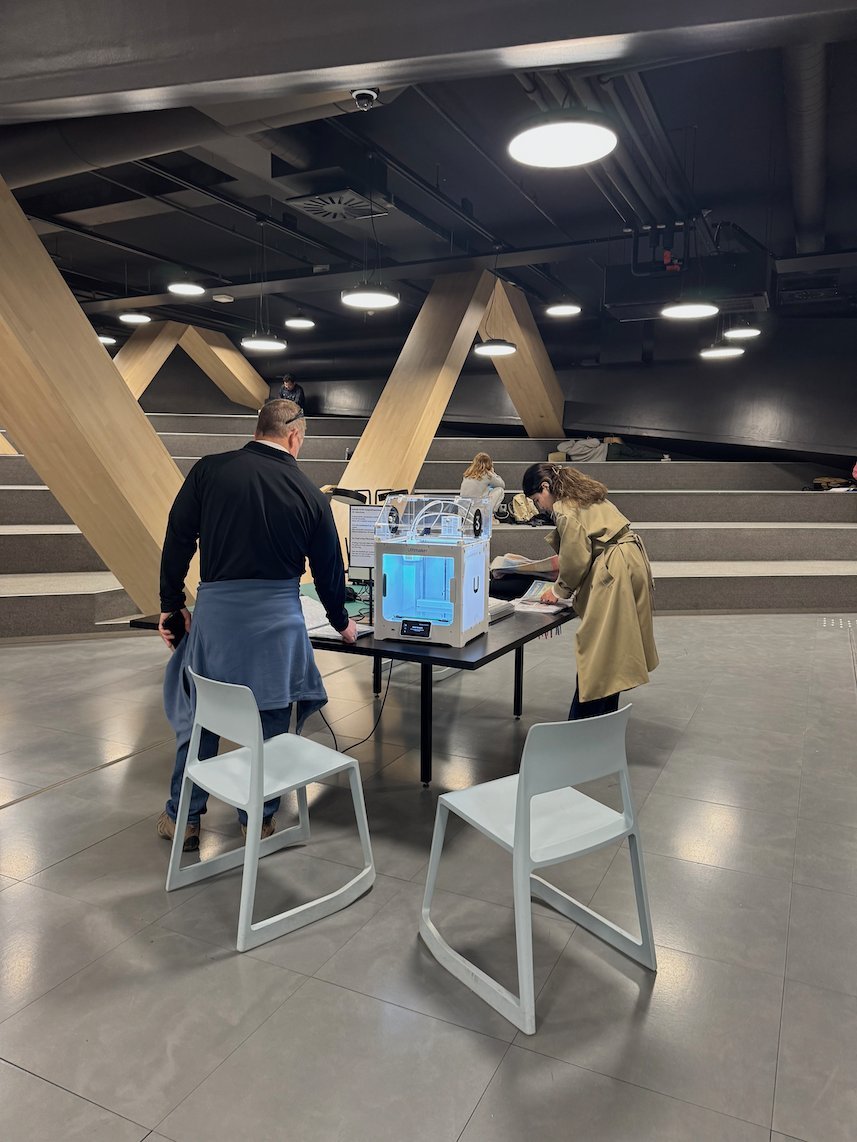Visitors work at a table with a machine in the Urban Workshop of Oodi library in Helsinki.