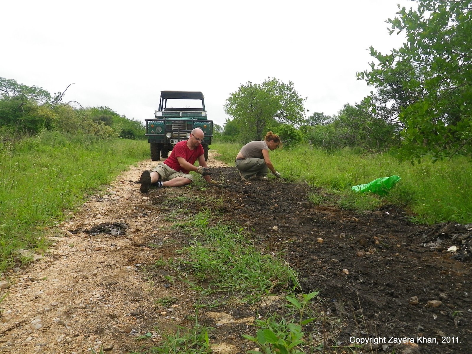 Students kneel by a Land Rover to repair a bush road near Hoedspruit.