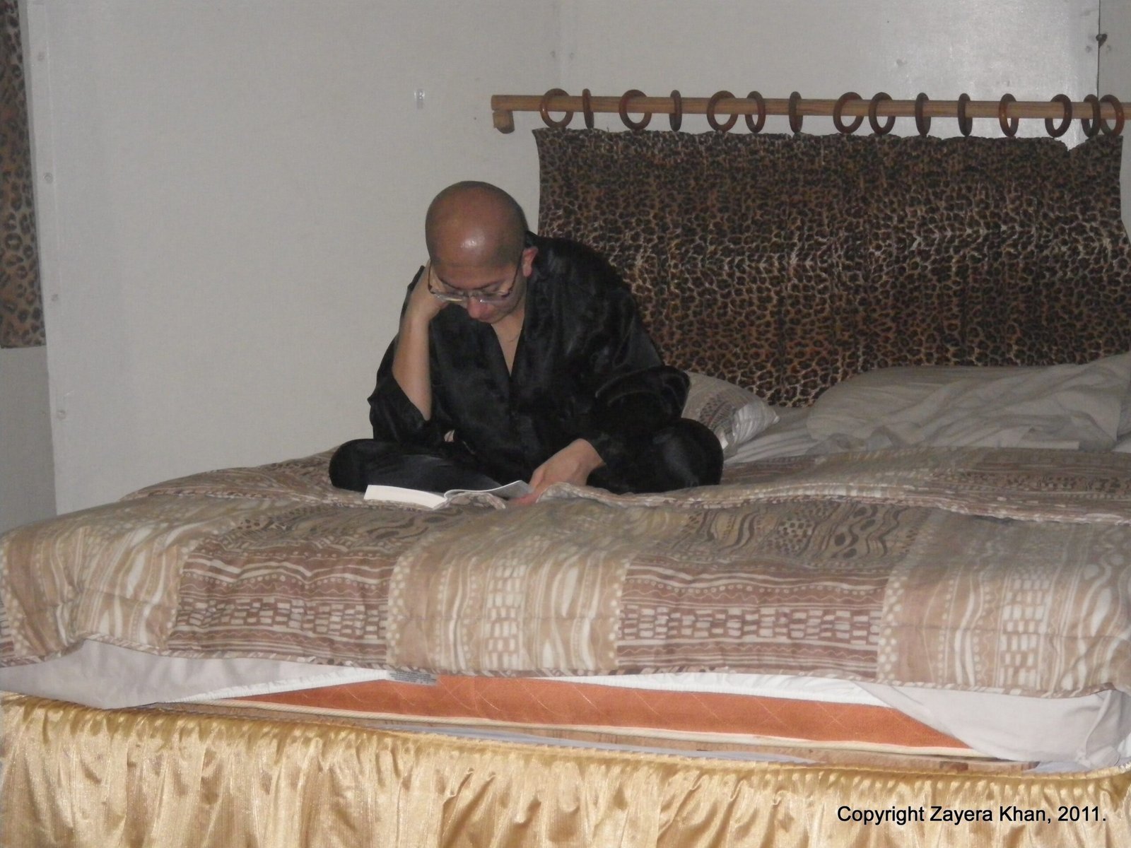 A traveler reads a book on a large bed in a room at the camp near Hoedspruit.
