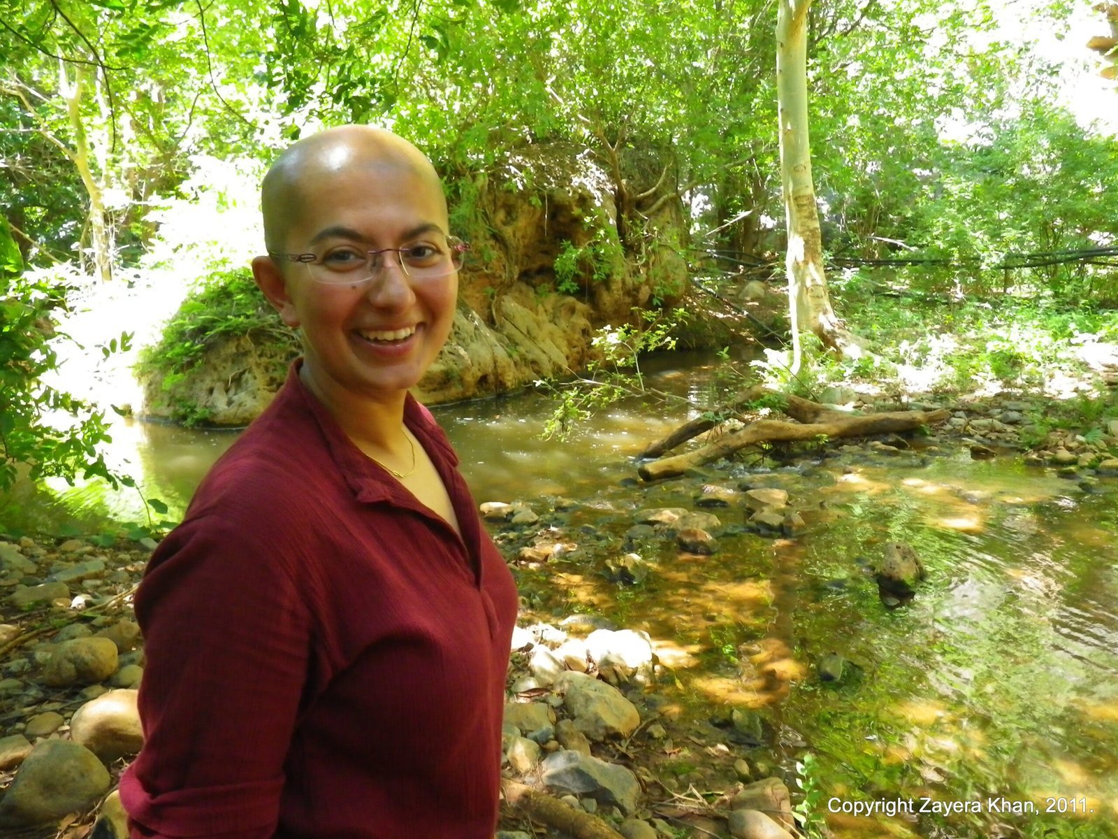 Zayera Khan smiles by a small stream in green bush near Hoedspruit, South Africa.
