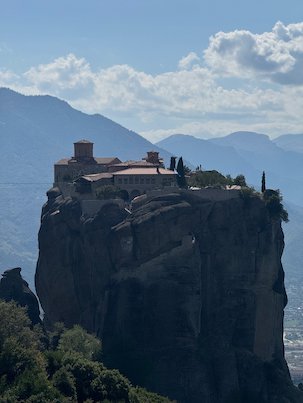 Holy Trinity Monastery on its rock pillar under white clouds at Meteora