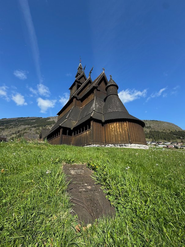 Hopperstad stave church seen from the grass below, with its dark tiered roofs