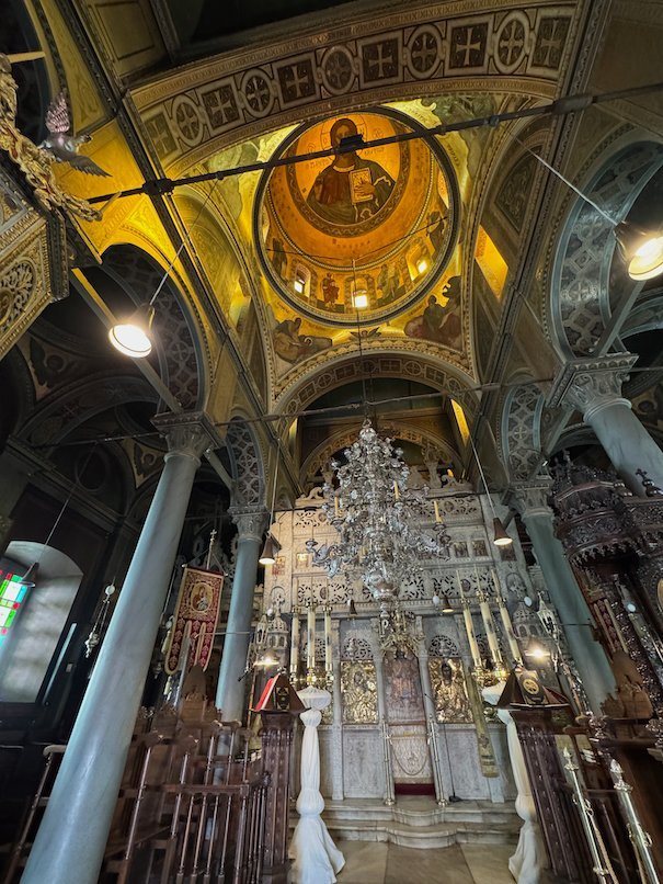 Inside the cathedral of Hydra, with a painted dome, columns and a silver chandelier