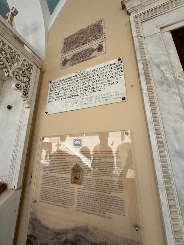 Marble plaques and a text panel on the wall of the cathedral in Hydra