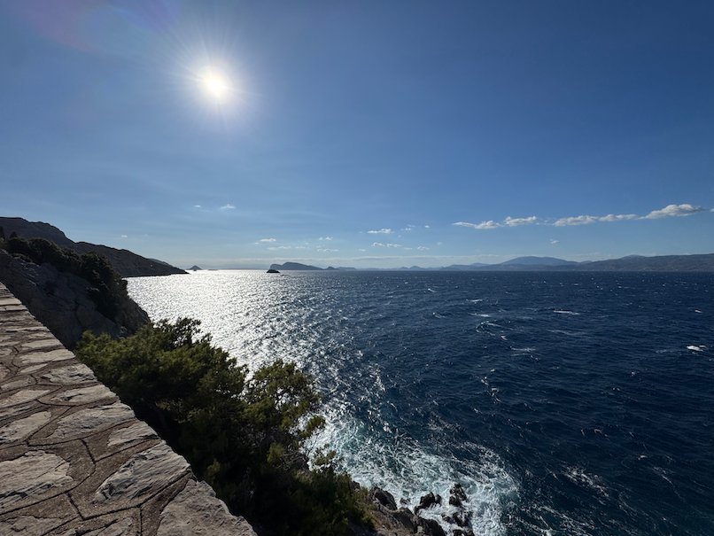Coastal path above the sea with bright sun on the water in Hydra