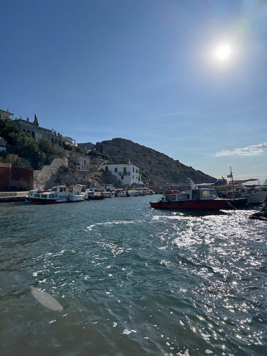 Boats in Hydra harbor with the sun over the hills