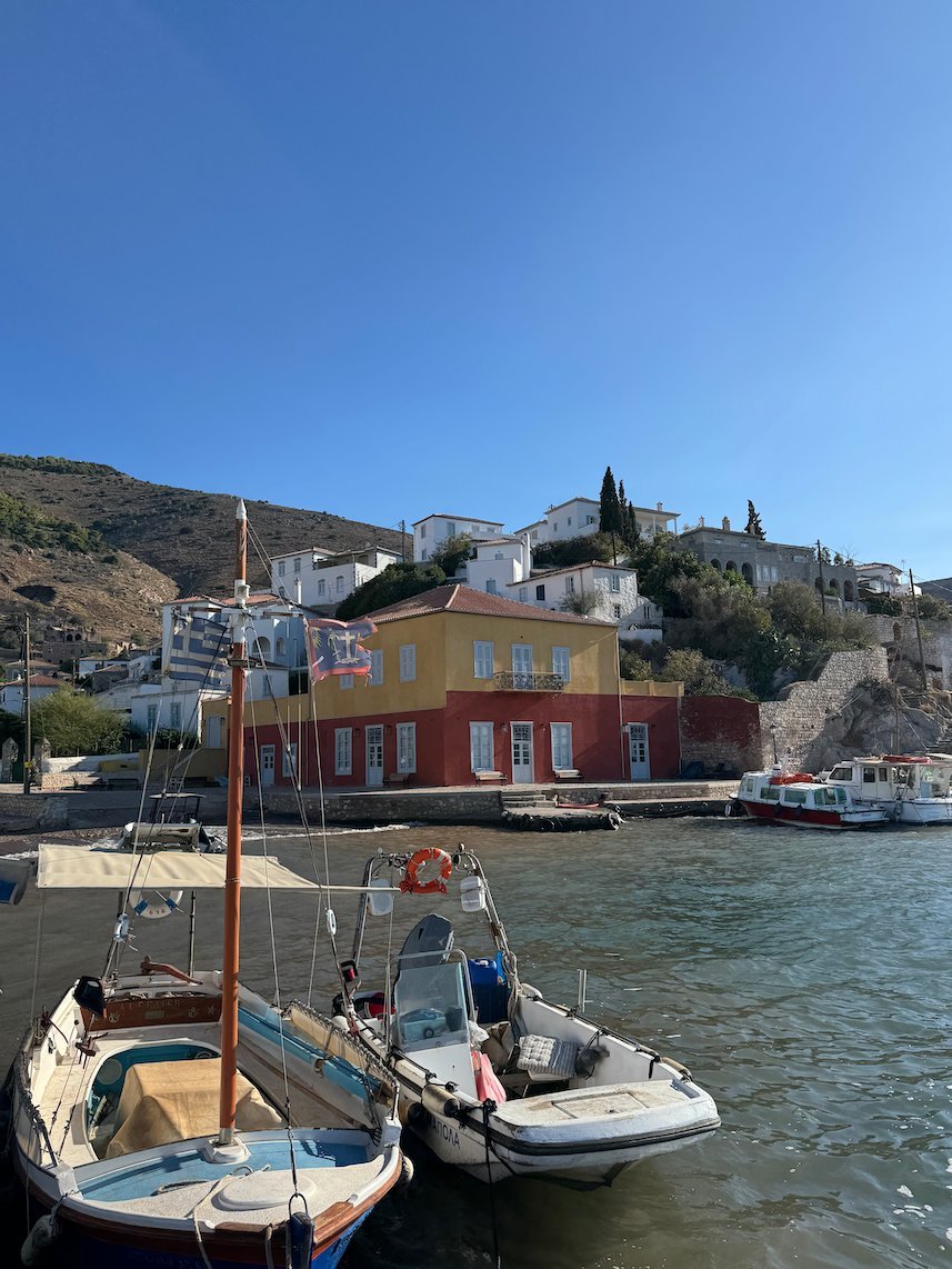 Small boats in Hydra harbor below a yellow and red house