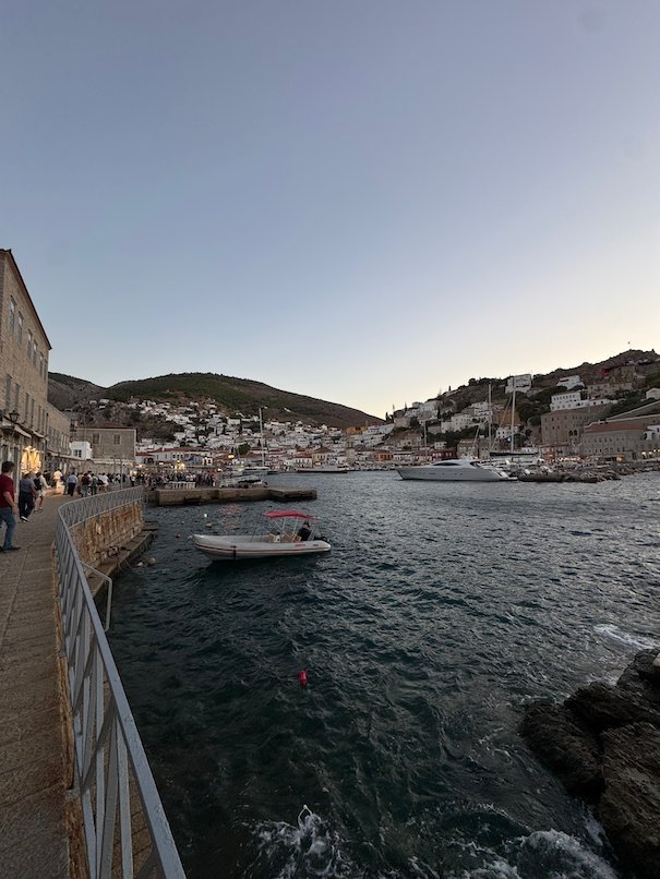Hydra harbor with small boats and houses on the hill in the evening