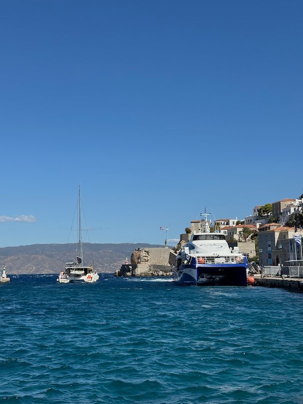 Fast ferry and a sailing boat by the harbor entrance of Hydra