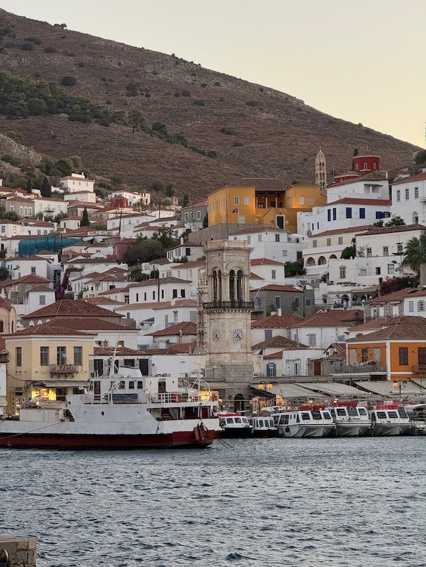 Hydra harbor, the clock tower and houses on the hill at dusk