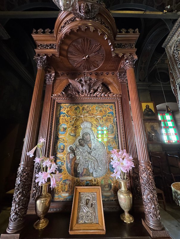 Icon in a carved wooden frame with flowers inside the cathedral of Hydra