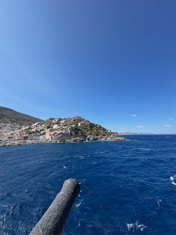 Old cannon that points to the sea, with Hydra town on the hill