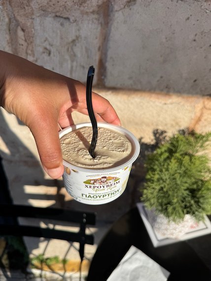 Hand that holds a cup of ice cream at a café table in Aegina