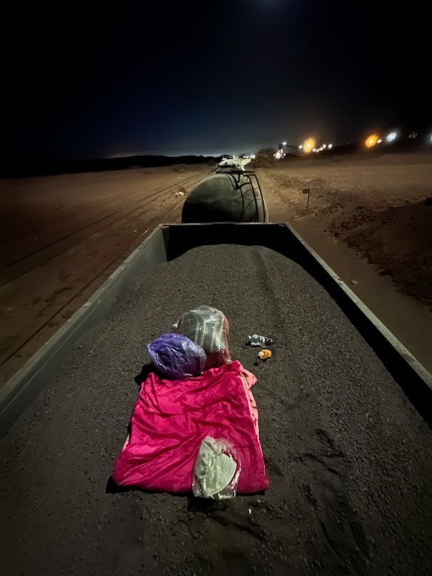 A pink sleeping bag lies on the ore inside an open wagon at night.