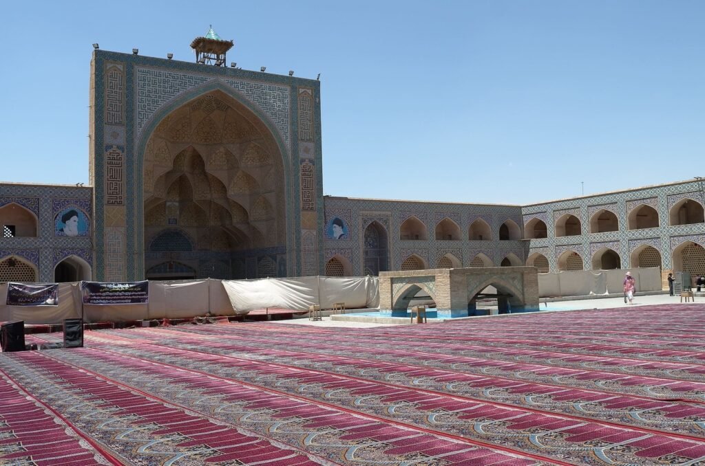 Courtyard with prayer carpets and a tiled iwan at the Jameh Mosque of Isfahan
