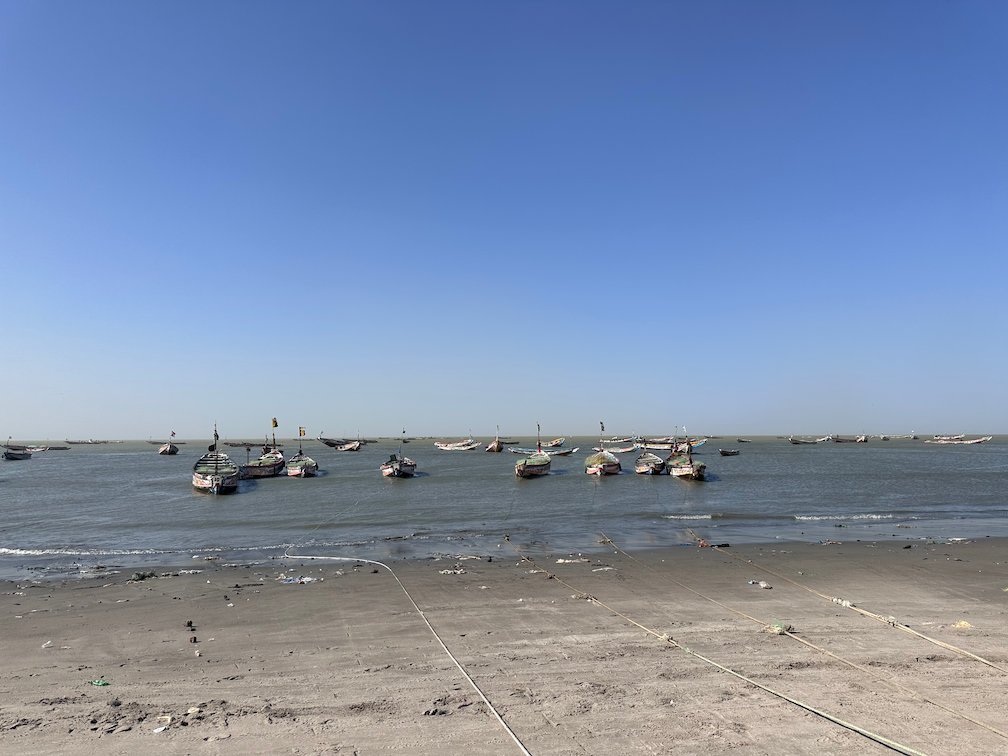 Pirogues lie at anchor in the water off the beach in Joal.
