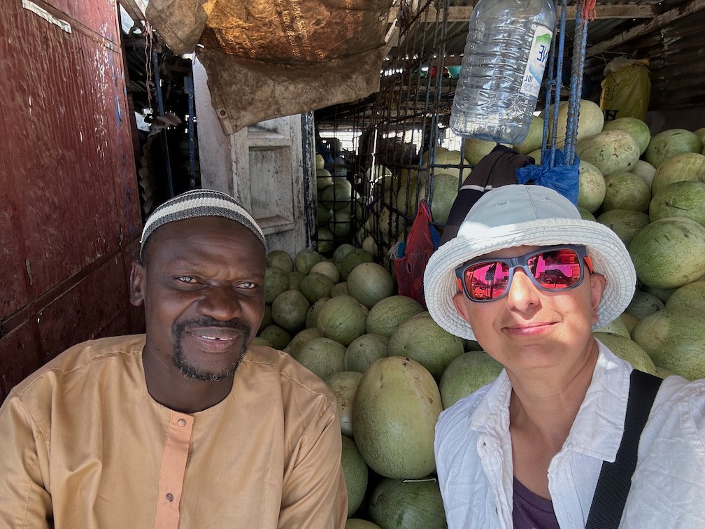 Zayera Khan takes a selfie with a watermelon vendor at his stall in Joal.