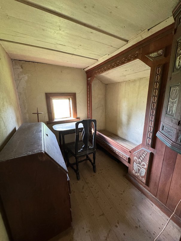 Old farmhouse room with a wooden desk, a chair and a built-in bed